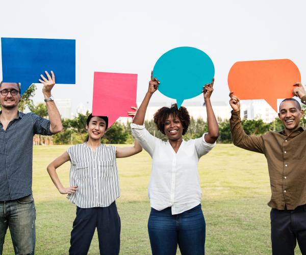 4 people standing holding paper speech bubbles