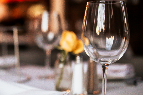 Table setting with wine glasses, flowers and other items that sit on a table