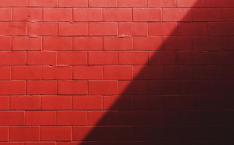 photo of a red brick wall that has the right half of the wall shadowed
