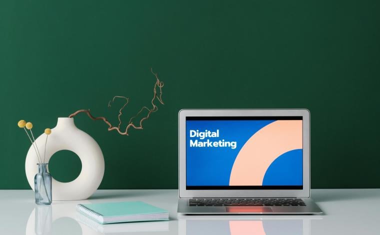 a laptop on a desk, the screen is open and says "digital marketing"