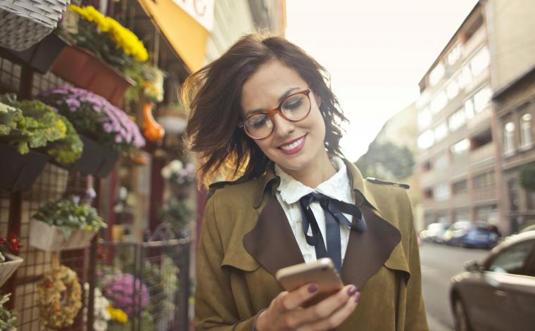 woman smiles while looking down at her phone