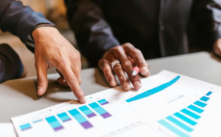 two people's hands touch a piece of paper with many graphs on it