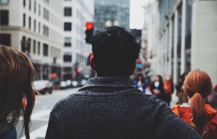 the back of someone's head as they walk among other people in a city