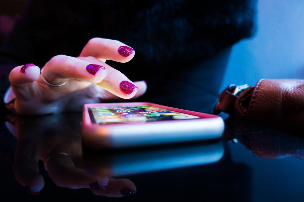 photo of a person with painted nails tapping on a phone