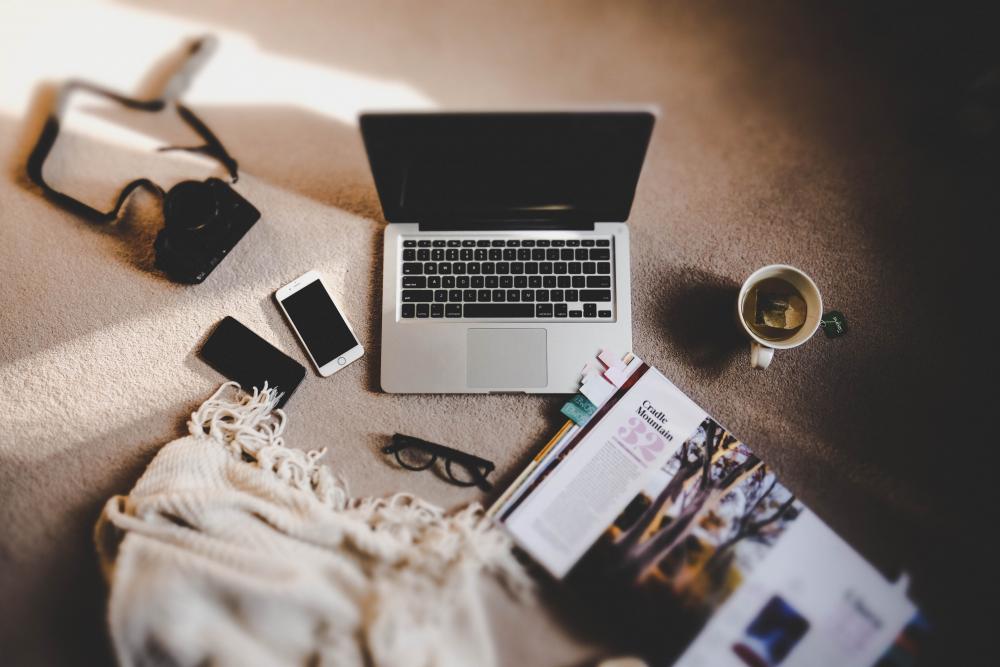 a bird's eye image of an open laptop with various office supplies littered around it