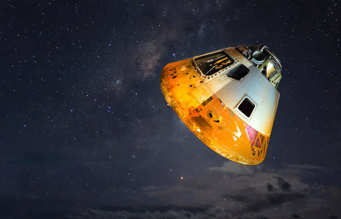 photo of a yellow and grey space capsule floating in a black sky