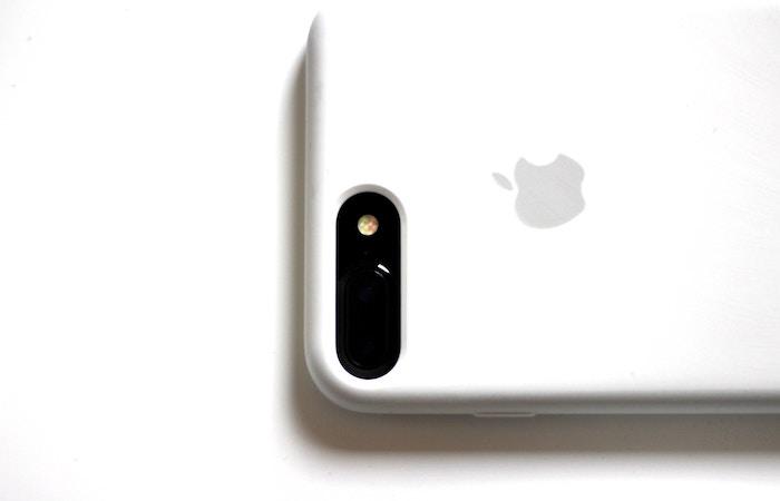 a white iphone with the screen facing down resting on a white surface