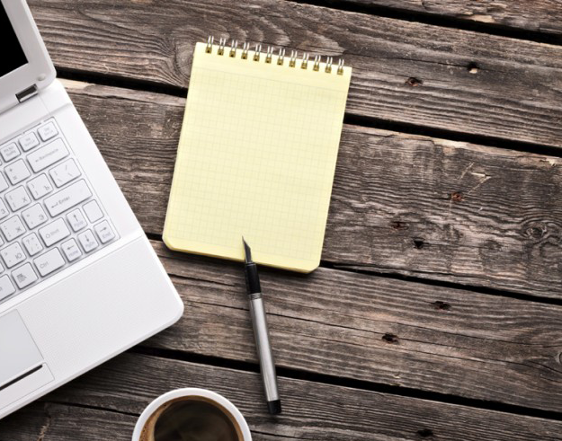 a laptop and an empty notepad laying flat next to each other